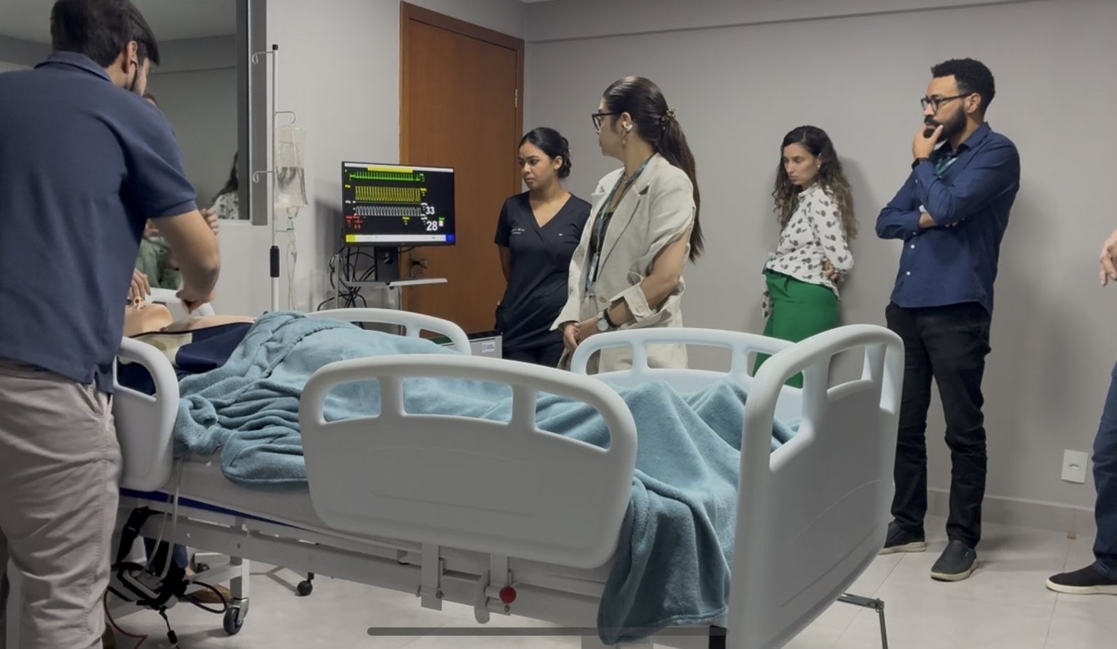 Sala de simulação realística com leito hospitalar e monitor multiparamétrico